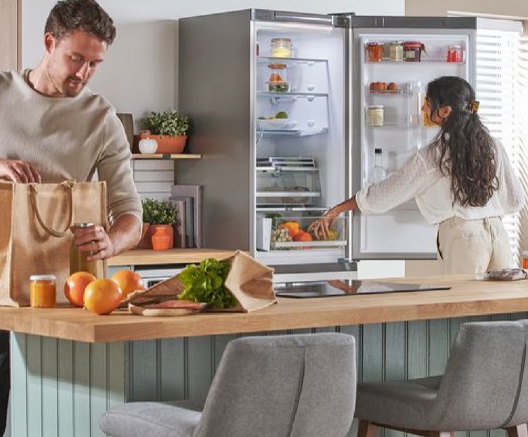 Una coppia in cucina davanti a un frigorifero aperto